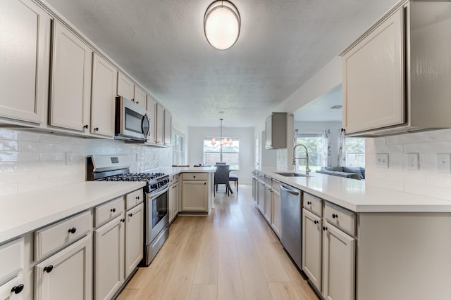 17814 Placid Oak Ct, Cypress, TX 77433 - kitchen featuring stainless steel appliances, a peninsula, light countertops, a chandelier, and backsplash