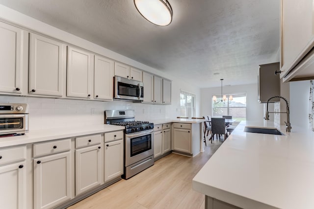 17814 Placid Oak Ct, Cypress, TX 77433 - kitchen featuring appliances with stainless steel finishes, a chandelier, decorative backsplash, a peninsula, and light countertops