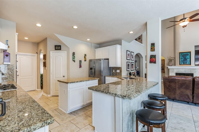 10906 Silverado Trace Dr, Houston, TX 77095 - kitchen featuring appliances with stainless steel finishes, arched walkways, a ceiling fan, a peninsula, and light stone countertops