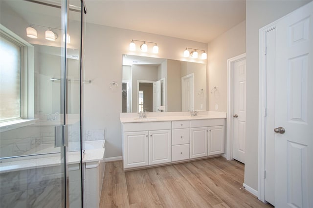 2926 Grand Hawthorne Rd, Conroe, TX 77385 - bathroom with double vanity, wood finished floors, a shower with door, and a bathtub