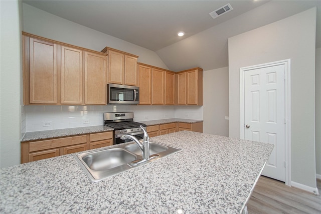 2926 Grand Hawthorne Rd, Conroe, TX 77385 - kitchen featuring stainless steel appliances, lofted ceiling, light wood finished floors, backsplash, and light brown cabinets