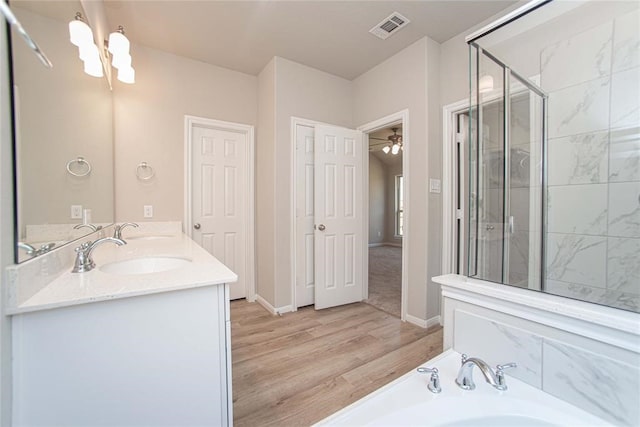 2926 Grand Hawthorne Rd, Conroe, TX 77385 - bathroom featuring a garden tub, wood finished floors, double vanity, a stall shower, and a chandelier