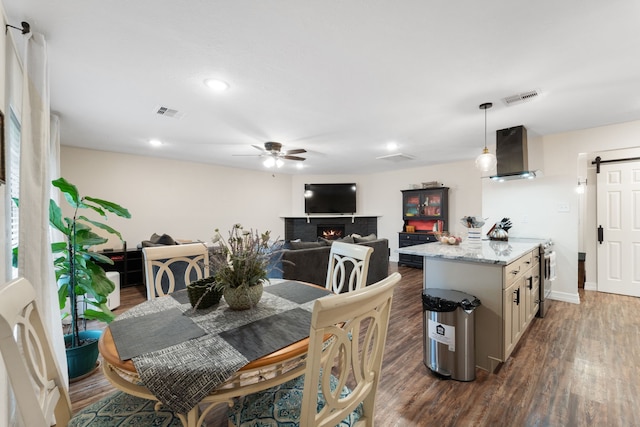 16230 Bowie Ridge Ln, Houston, TX 77053 - dining room with ceiling fan, dark wood-style flooring, a barn door, a warm lit fireplace, and recessed lighting