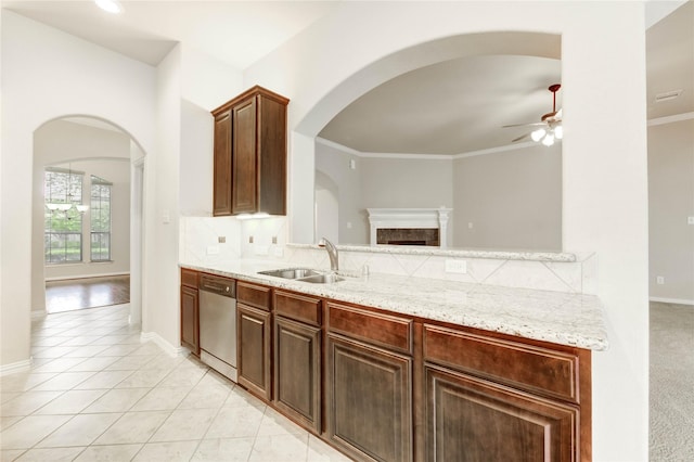 634 Oak Ridge Grove Cir, Spring, TX 77386 - kitchen with stainless steel dishwasher, ceiling fan, a fireplace, light stone counters, and arched walkways