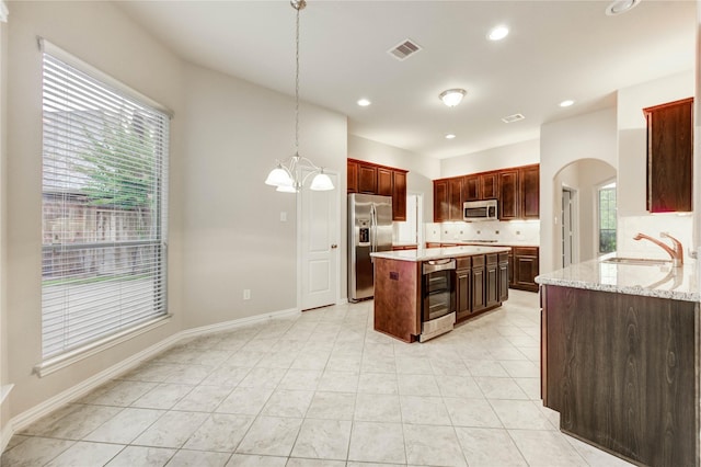 634 Oak Ridge Grove Cir, Spring, TX 77386 - kitchen with appliances with stainless steel finishes, decorative backsplash, beverage cooler, arched walkways, and light stone countertops