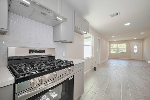 11311 Raincove Dr, Houston, TX 77016 - kitchen with stainless steel gas range oven, extractor fan, tasteful backsplash, light wood-style floors, and recessed lighting