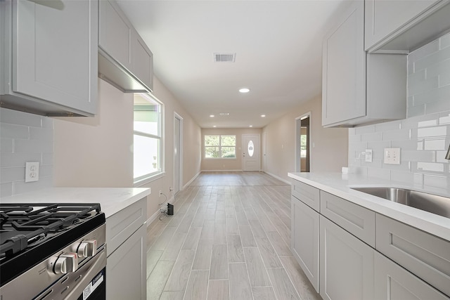 11311 Raincove Dr, Houston, TX 77016 - kitchen with light countertops, backsplash, recessed lighting, light wood finished floors, and stainless steel gas range oven