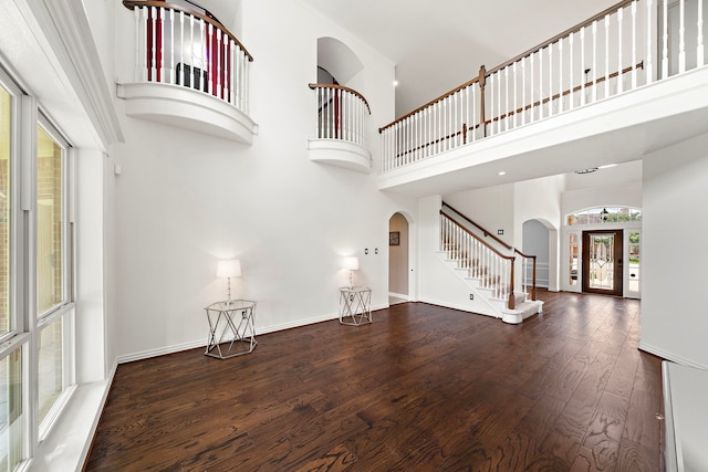 18806 Manleigh Ct, Tomball, TX 77377 - unfurnished living room featuring arched walkways, stairs, wood finished floors, and a towering ceiling