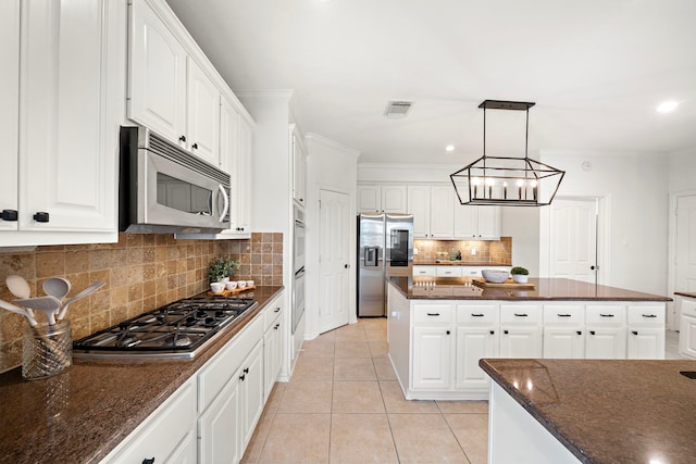 18806 Manleigh Ct, Tomball, TX 77377 - kitchen featuring stainless steel appliances, a center island, decorative backsplash, light tile patterned floors, and white cabinetry