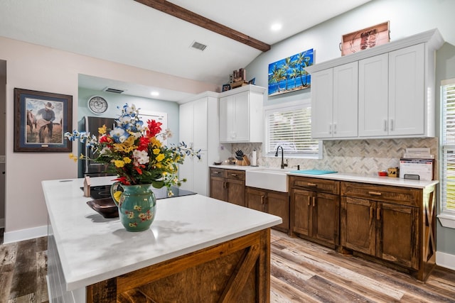 137 County Road 3665, Splendora, TX 77372 - kitchen featuring a center island, light wood-type flooring, light countertops, tasteful backsplash, and white cabinets