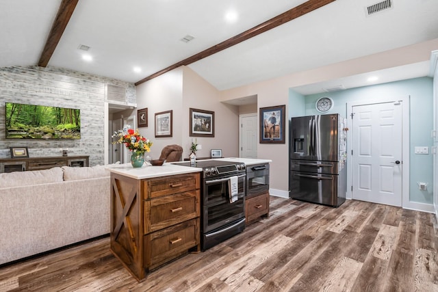 137 County Road 3665, Splendora, TX 77372 - kitchen featuring refrigerator with ice dispenser, stainless steel range with electric stovetop, open floor plan, wood finished floors, and an accent wall