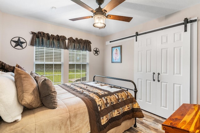 137 County Road 3665, Splendora, TX 77372 - bedroom featuring a barn door, wood finished floors, a ceiling fan, and a closet