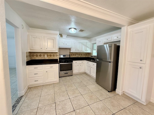 5701 Luna St, Houston, TX 77076 - kitchen with stainless steel appliances, dark countertops, decorative backsplash, and white cabinetry