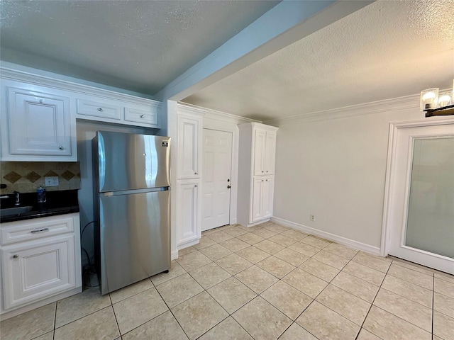 5701 Luna St, Houston, TX 77076 - kitchen featuring freestanding refrigerator, light tile patterned floors, white cabinets, backsplash, and a textured ceiling