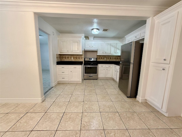 5701 Luna St, Houston, TX 77076 - kitchen with appliances with stainless steel finishes, dark countertops, light tile patterned flooring, white cabinetry, and ornamental molding
