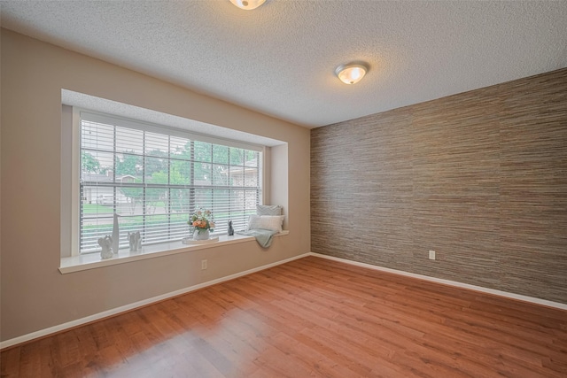 3031 The Highlands Dr, Sugar Land, TX 77478 - spare room featuring wood finished floors, a textured ceiling, and an accent wall