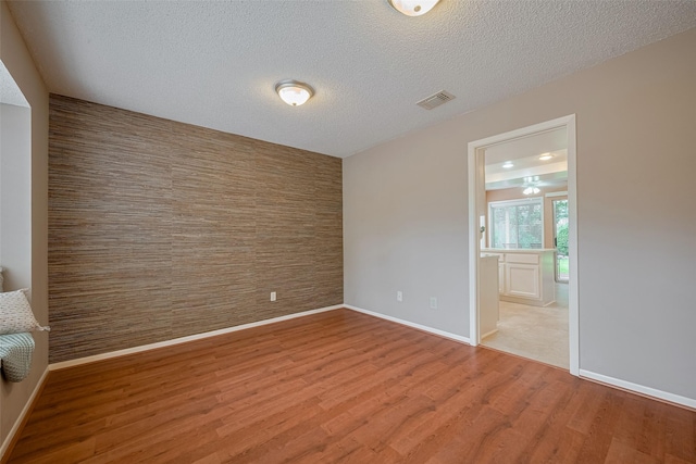 3031 The Highlands Dr, Sugar Land, TX 77478 - unfurnished room featuring wood finished floors, a textured ceiling, and an accent wall