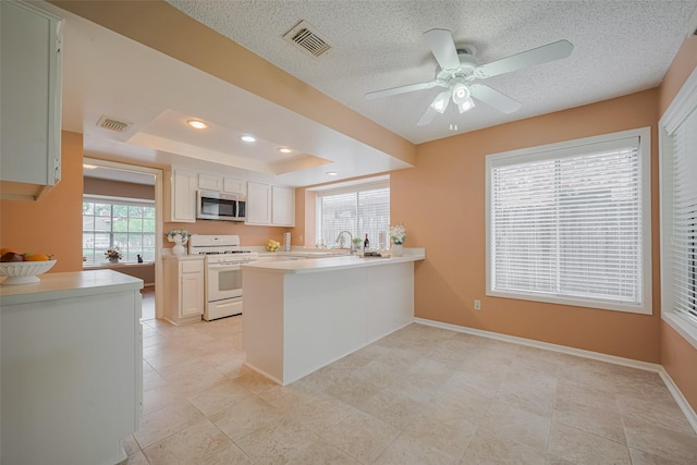 3031 The Highlands Dr, Sugar Land, TX 77478 - kitchen with white gas stove, stainless steel microwave, a peninsula, light countertops, and a ceiling fan