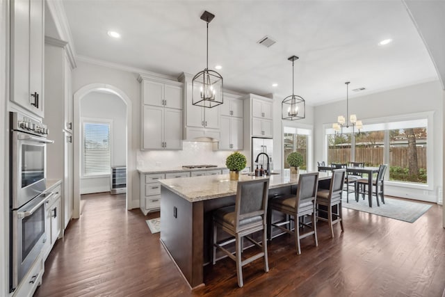 1746 Du Barry Ln, Houston, TX 77018 - kitchen with stainless steel appliances, arched walkways, a chandelier, healthy amount of natural light, and ornamental molding