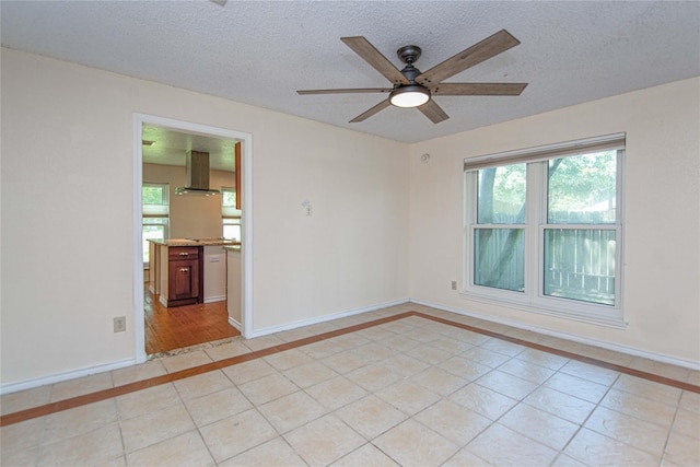 25418 Sugar Valley Ln, Spring, TX 77373 - empty room with inlaid floor details, ceiling fan, light tile patterned floors, healthy amount of natural light, and a textured ceiling