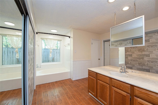 25418 Sugar Valley Ln, Spring, TX 77373 - full bath featuring a bath, a textured ceiling, vanity, wood finished floors, and a wainscoted wall