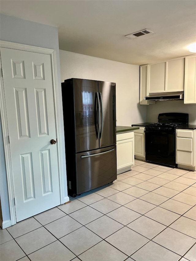 132 Grothe Ln, Houston, TX 77022 - kitchen with freestanding refrigerator, black gas range, under cabinet range hood, dark countertops, and light tile patterned floors