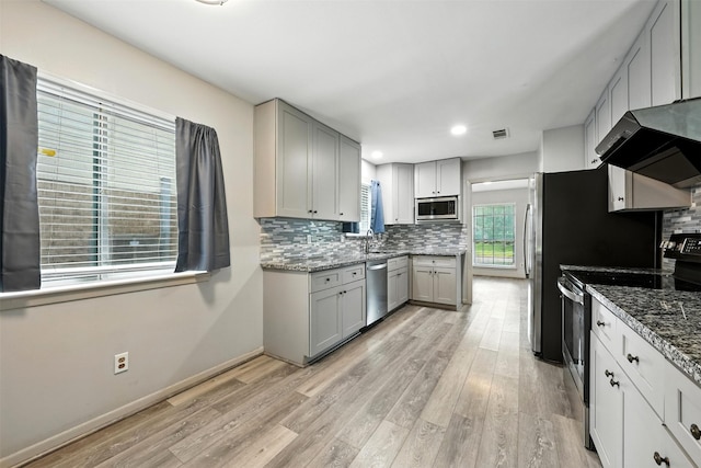 8503 Leader St, Houston, TX 77036 - kitchen with stainless steel appliances, wall chimney range hood, gray cabinets, light wood finished floors, and recessed lighting