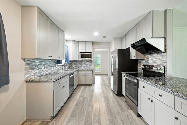 8503 Leader St, Houston, TX 77036 - kitchen with appliances with stainless steel finishes, exhaust hood, light stone countertops, light wood-style flooring, and backsplash