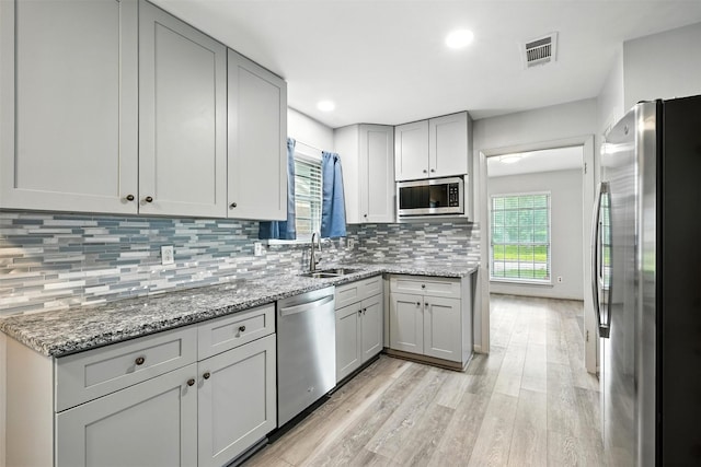 8503 Leader St, Houston, TX 77036 - kitchen featuring stainless steel appliances, light wood-style flooring, backsplash, light stone counters, and recessed lighting