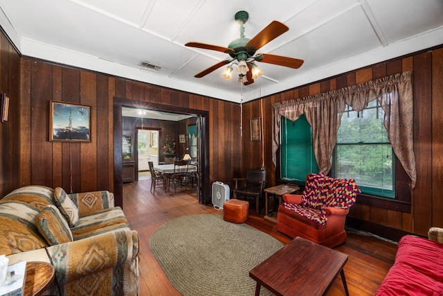 600 Brazos St, Glidden, TX 78943 - living area featuring wood walls, a ceiling fan, healthy amount of natural light, and hardwood / wood-style floors