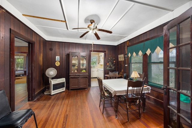 600 Brazos St, Glidden, TX 78943 - dining area featuring heating unit, ceiling fan, wood walls, and dark wood-type flooring