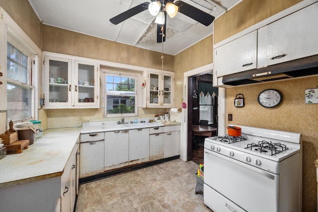 600 Brazos St, Glidden, TX 78943 - kitchen featuring white range with gas cooktop, light countertops, under cabinet range hood, and white cabinetry