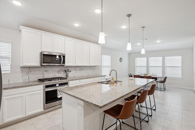 1502 Trails Of Katy Ln, Katy, TX 77494 - kitchen featuring appliances with stainless steel finishes, backsplash, a kitchen island with sink, light tile patterned flooring, and recessed lighting