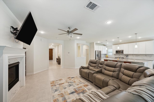 1502 Trails Of Katy Ln, Katy, TX 77494 - living room featuring ceiling fan, light tile patterned floors, arched walkways, recessed lighting, and a premium fireplace