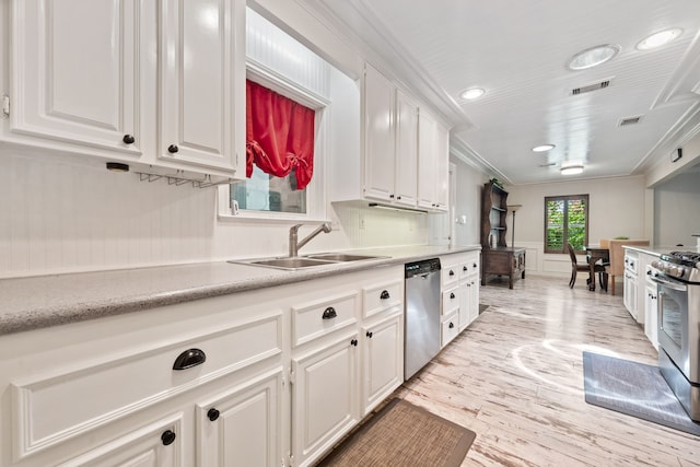150 Greenbriar Dr, Montgomery, TX 77356 - kitchen featuring stainless steel appliances, white cabinetry, light wood-style floors, light countertops, and a wainscoted wall
