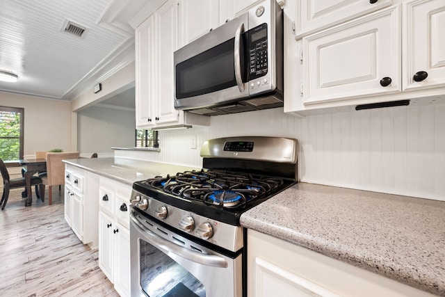 150 Greenbriar Dr, Montgomery, TX 77356 - kitchen with appliances with stainless steel finishes, white cabinets, light wood-type flooring, light stone counters, and crown molding