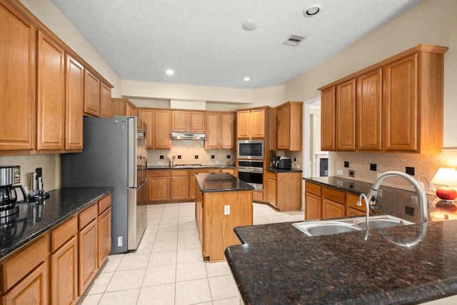 18718 Glenn Haven Estates Dr, Spring, TX 77379 - kitchen featuring appliances with stainless steel finishes, light tile patterned floors, under cabinet range hood, backsplash, and a center island