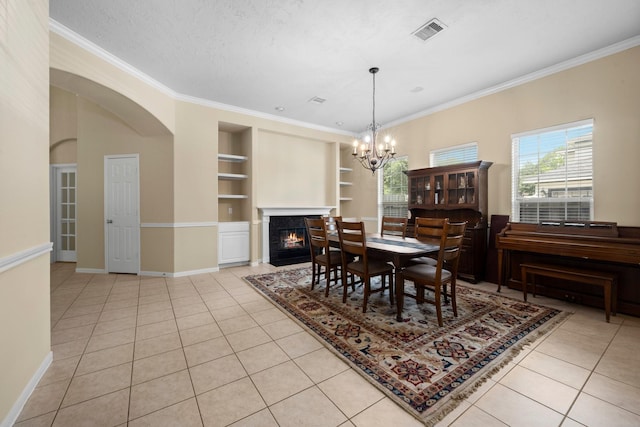 18718 Glenn Haven Estates Dr, Spring, TX 77379 - dining room featuring built in features, light tile patterned flooring, crown molding, a chandelier, and a fireplace with flush hearth