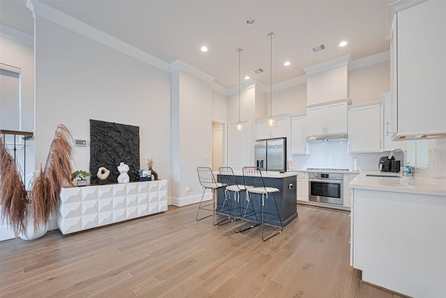 5308 S Capitol St, Houston, TX 77023 - kitchen featuring appliances with stainless steel finishes, a kitchen breakfast bar, ornamental molding, light countertops, and white cabinetry