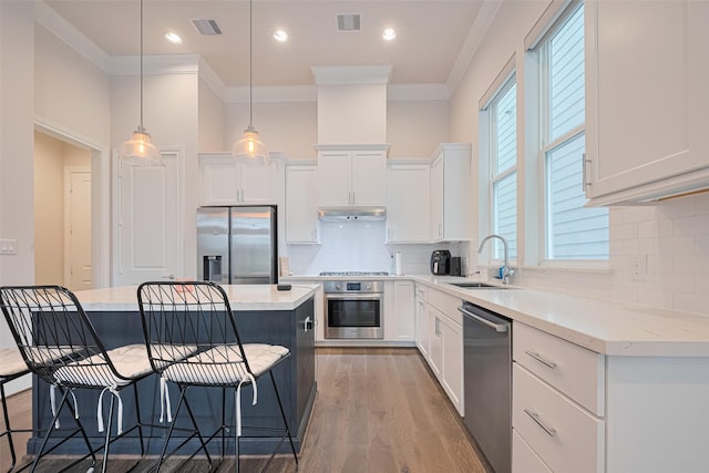 5308 S Capitol St, Houston, TX 77023 - kitchen featuring appliances with stainless steel finishes, a kitchen breakfast bar, light wood finished floors, crown molding, and white cabinets
