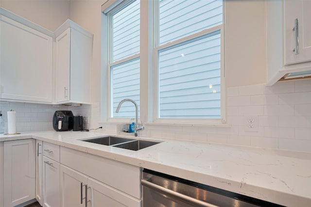 5308 S Capitol St, Houston, TX 77023 - kitchen with stainless steel dishwasher, white cabinets, tasteful backsplash, and light stone counters