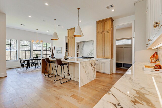 6911 Hartland Ave, Houston, TX 77055 - kitchen with plenty of natural light, an island with sink, light wood-style floors, recessed lighting, and light stone counters