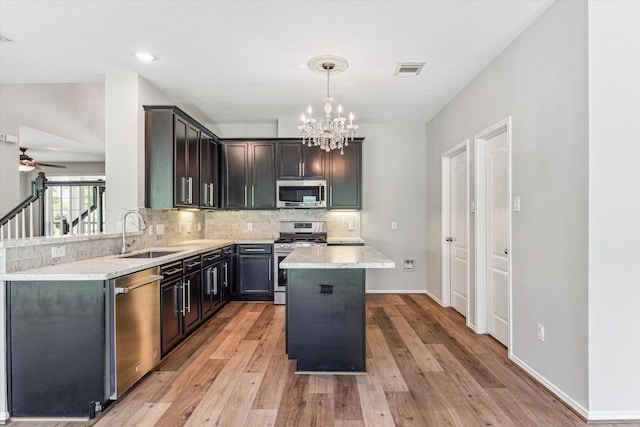 2551 Goldeneye Ln, League City, TX 77573 - kitchen featuring appliances with stainless steel finishes, a chandelier, decorative backsplash, light countertops, and a kitchen island