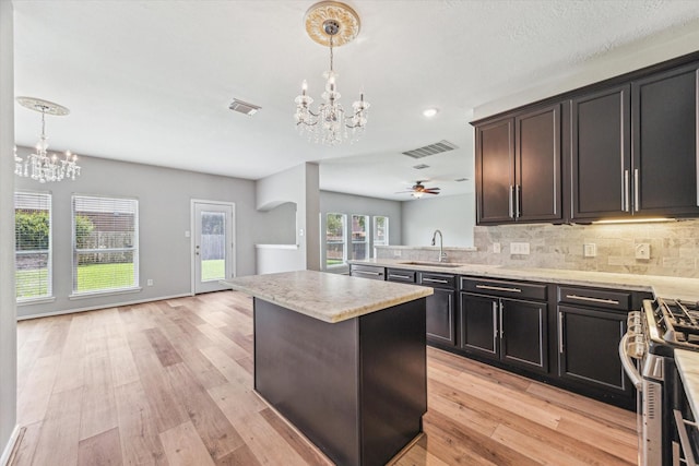 2551 Goldeneye Ln, League City, TX 77573 - kitchen with a chandelier, appliances with stainless steel finishes, a center island, backsplash, and light wood-style flooring