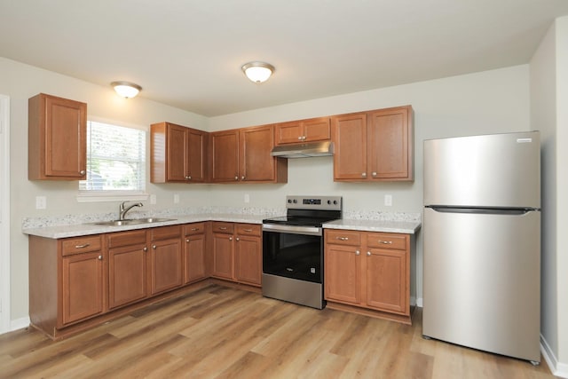 1440 Shepherd St, Hempstead, TX 77445 - kitchen featuring appliances with stainless steel finishes, under cabinet range hood, light wood-style floors, and brown cabinets