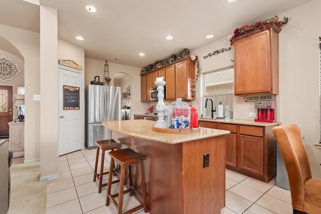 14306 Prosper Ridge Dr, Cypress, TX 77429 - kitchen with appliances with stainless steel finishes, light tile patterned floors, arched walkways, a kitchen island, and recessed lighting