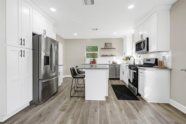 2346 Delafield St, Houston, TX 77023 - kitchen featuring appliances with stainless steel finishes, open shelves, a center island, tasteful backsplash, and white cabinetry