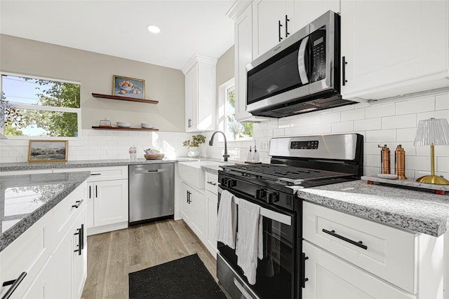 2346 Delafield St, Houston, TX 77023 - kitchen featuring stainless steel appliances, light wood-style flooring, backsplash, healthy amount of natural light, and recessed lighting