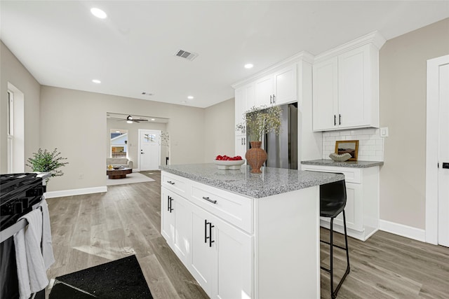 2346 Delafield St, Houston, TX 77023 - kitchen with stainless steel refrigerator, range, light wood finished floors, light stone countertops, and a kitchen island