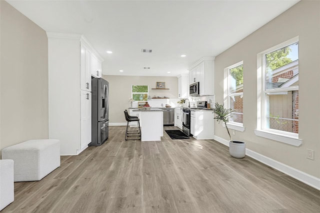 2346 Delafield St, Houston, TX 77023 - kitchen with appliances with stainless steel finishes, open shelves, a breakfast bar, white cabinets, and light wood finished floors